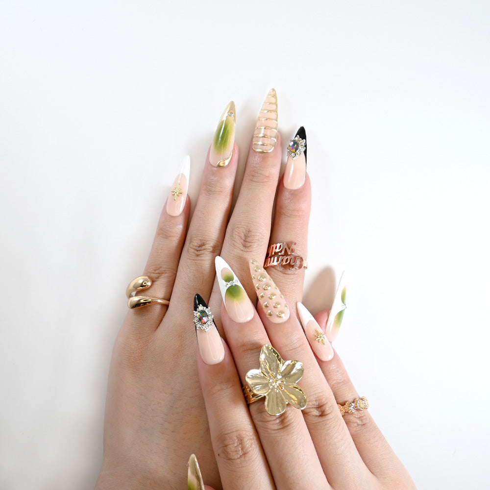 Elegant press-on nails in nude, green, and gold with rhinestones and textured 3D studs