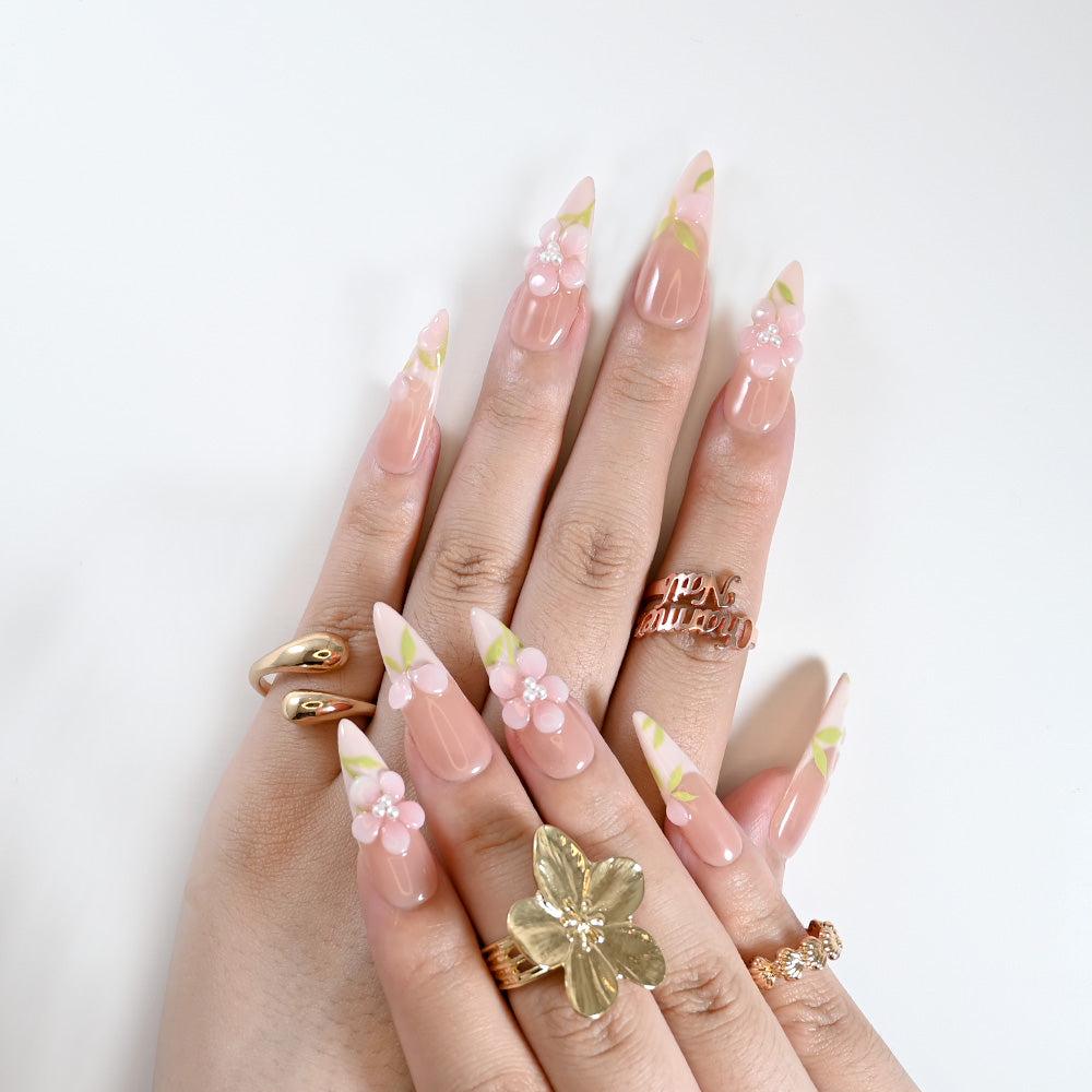 Romantic spring nails with nude base, pink blossoms, and pearl embellishments