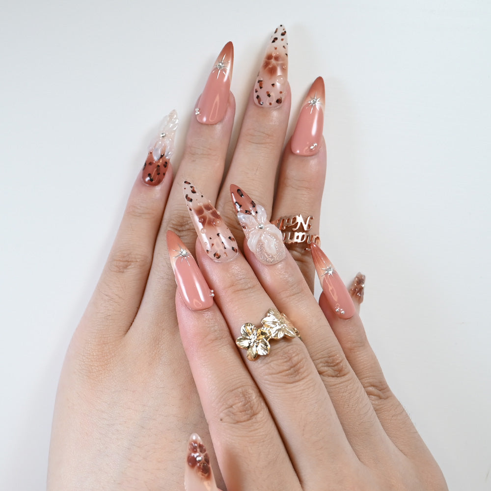 Long stiletto nude nails with brown floral art and metallic star studs