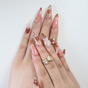 Long stiletto nude nails with brown floral art and metallic star studs