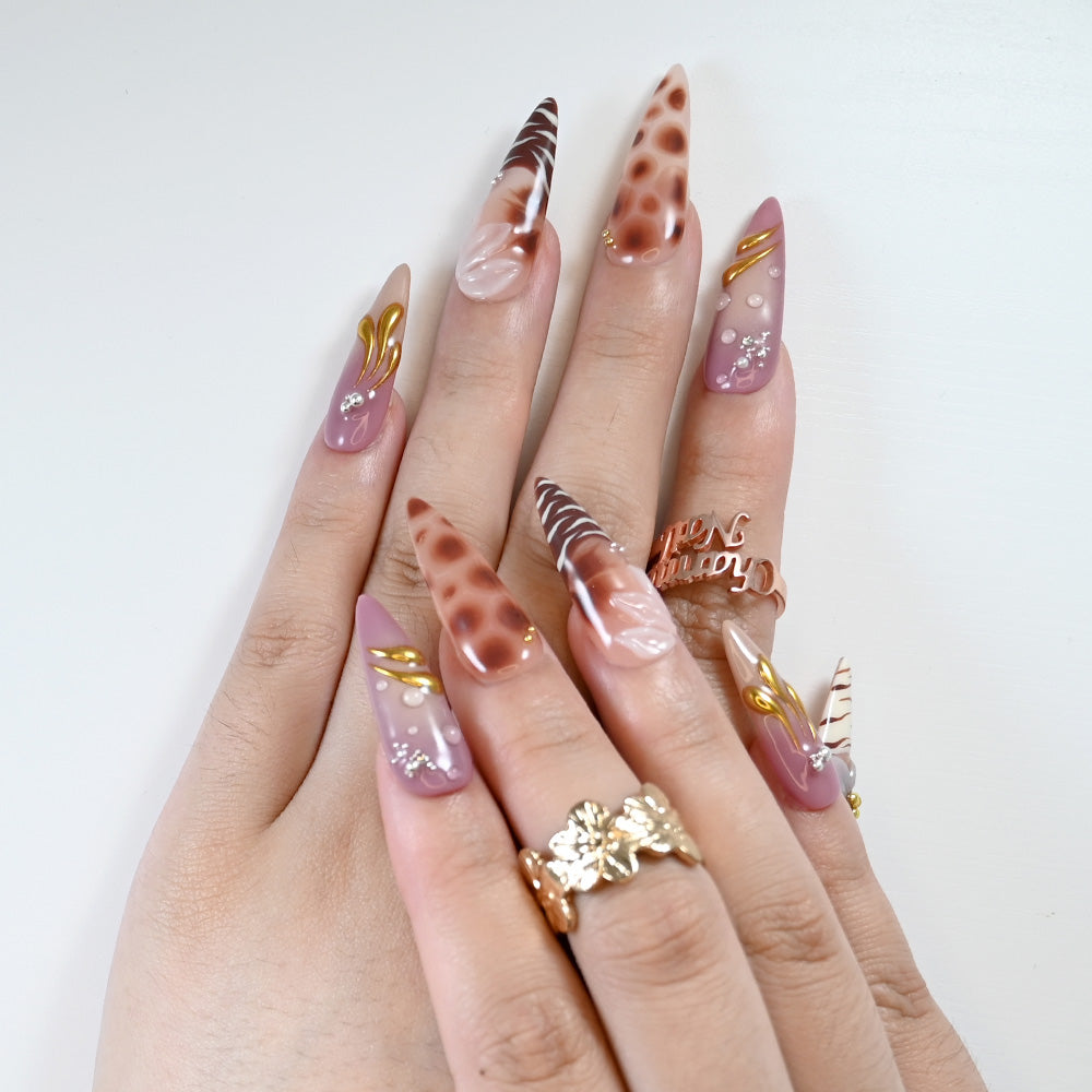 Elegant long press-on nails featuring zebra stripes, leopard spots, and gold charm"