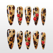 Leopard print press-on nails with 3D cherry accents and gold shimmer