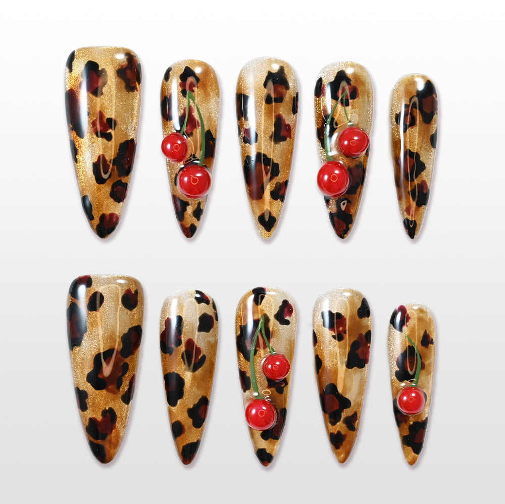 Leopard print press-on nails with 3D cherry accents and gold shimmer