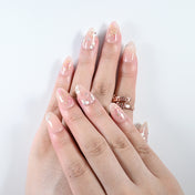 Elegant press-on nails with blush base, gold sparkle, and dainty flowers