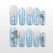 Icy blue metallic press-on nails with pearls, rhinestone cross, and 3D floral accents