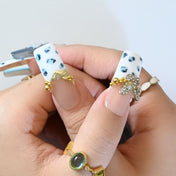 Luxury blue and white press-on nails featuring leopard spots, gold beads, and ombre art