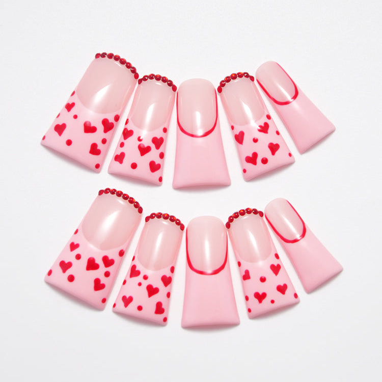 Short square press-on nails with pink French tips and red heart patterns