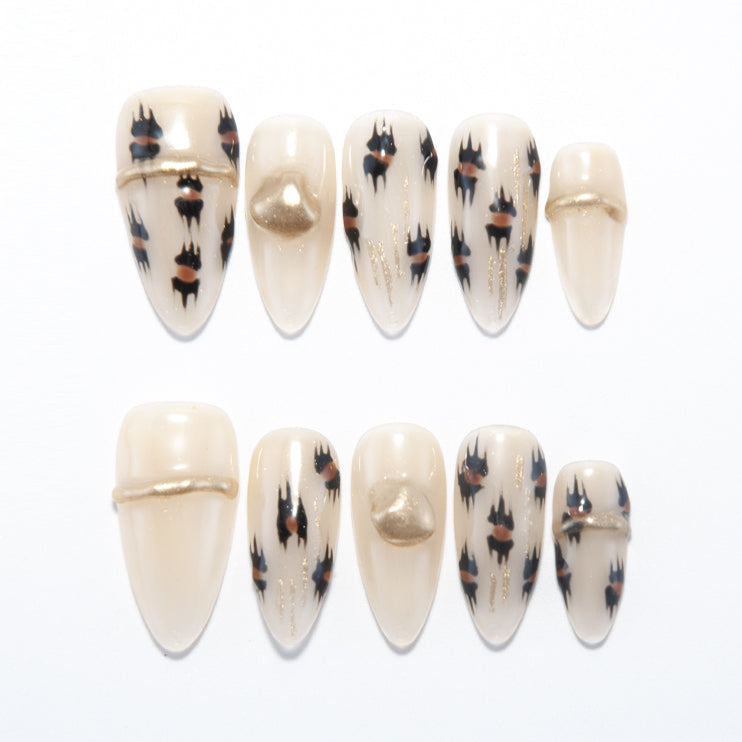 Beige press-on nails with black and brown leopard print and gold metallic accents