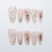Nude pink press-on nails with white floral design and gold foil