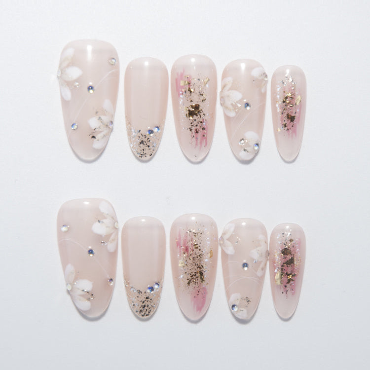 Nude pink press-on nails with white floral design and gold foil