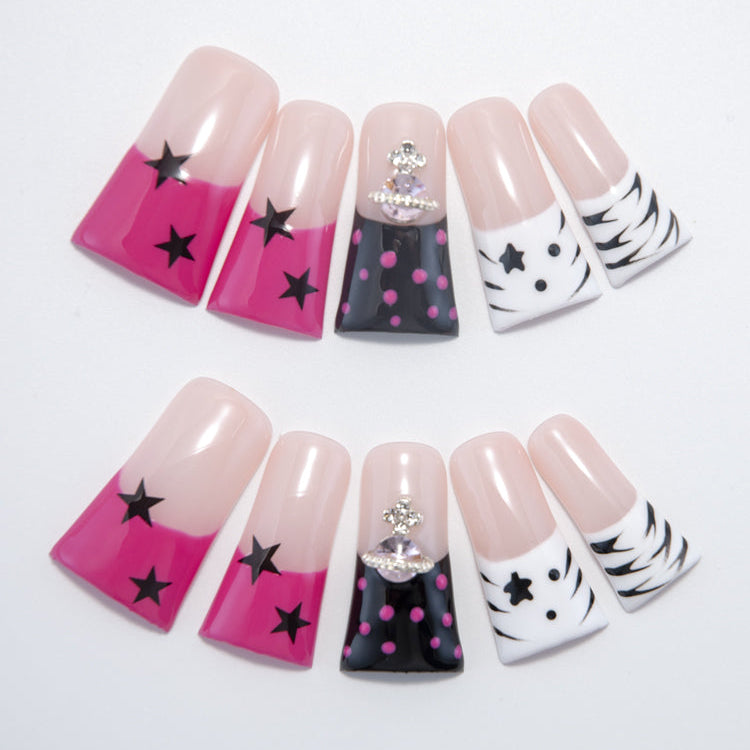 Square press-on nails with pink star tips, black polka dots, and gemstone charm