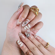 Elegant nude press-on nails with rhinestone star, pearl chains, and white wrap design