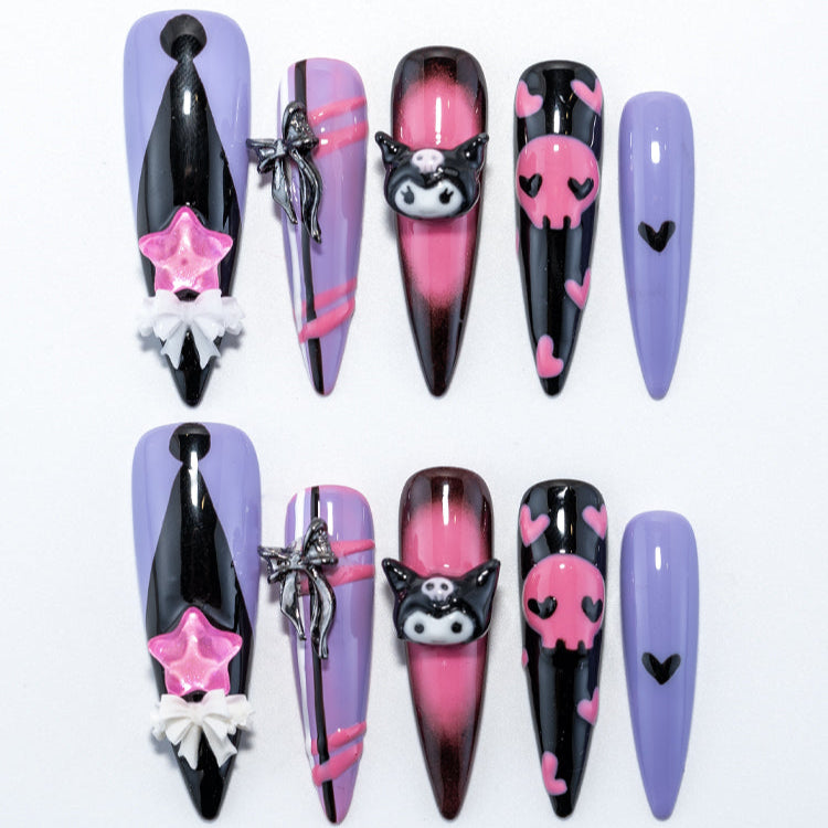 Purple and black press-on nails with Kuromi charm, pink skull hearts, and silver bow details