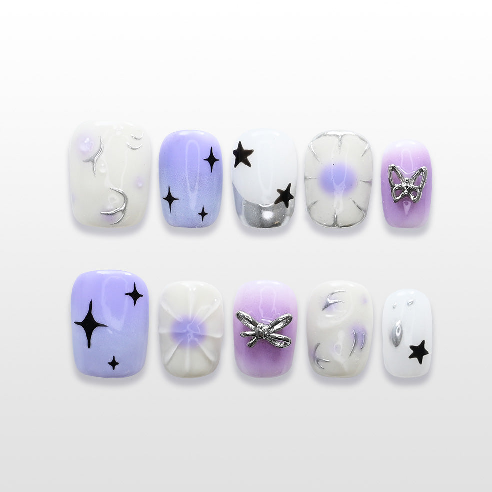 Purple and white gradient press-on nails with black star designs and silver butterfly charm